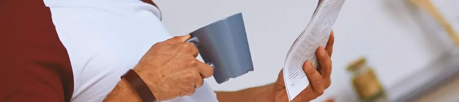 Man drinking from mug while reading a booklet